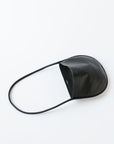 A black leather shoulder bag rests on a white background. The leather is soft and shiny, and the bag is a half moon shape.