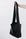 A woman's arm is visible, holding out the strap of a large, soft black leather shoulder bag.