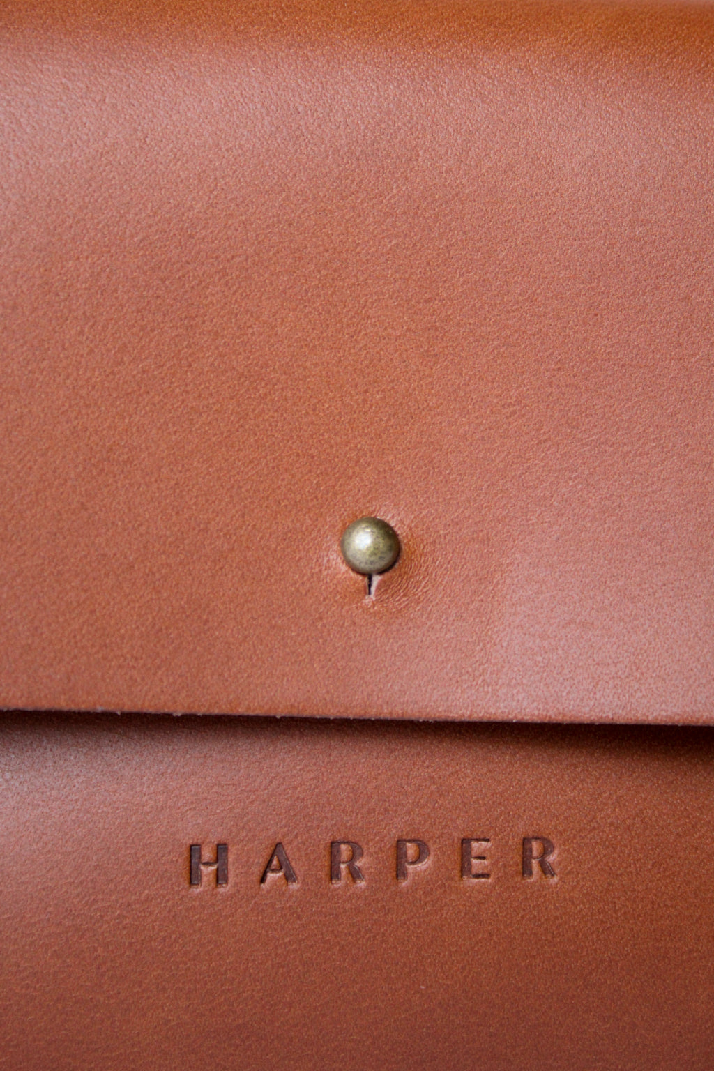 A detail of the "Harper" logo heat stamped on soft brown leather.
