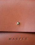 A detail of the "Harper" logo heat stamped on soft brown leather.