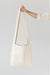 A woman's arm is visible, holding out the strap of a large, soft undyed, natural leather shoulder bag.