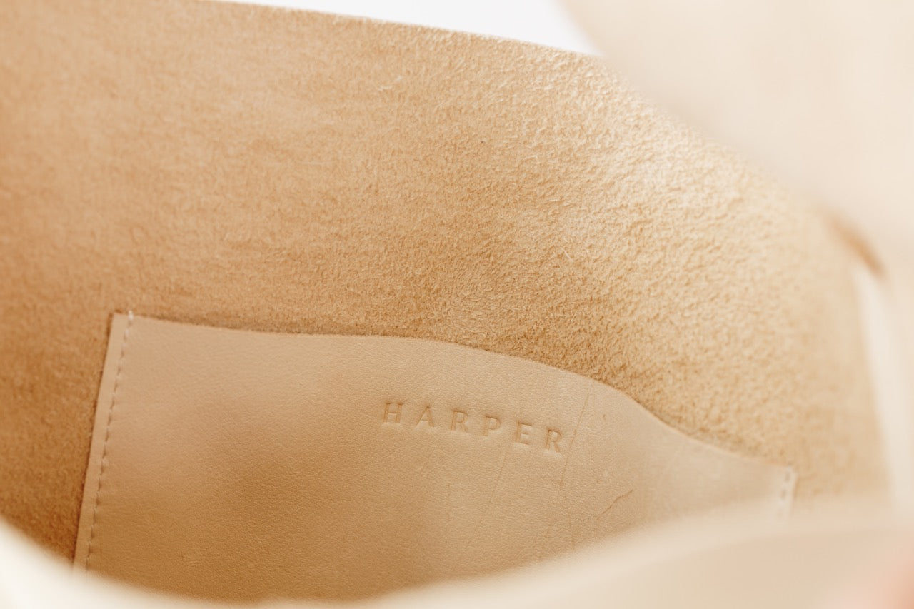 The interior of large, soft undyed leather shoulder bag, showing the inside pocket with stitching and the "Harper" logo.