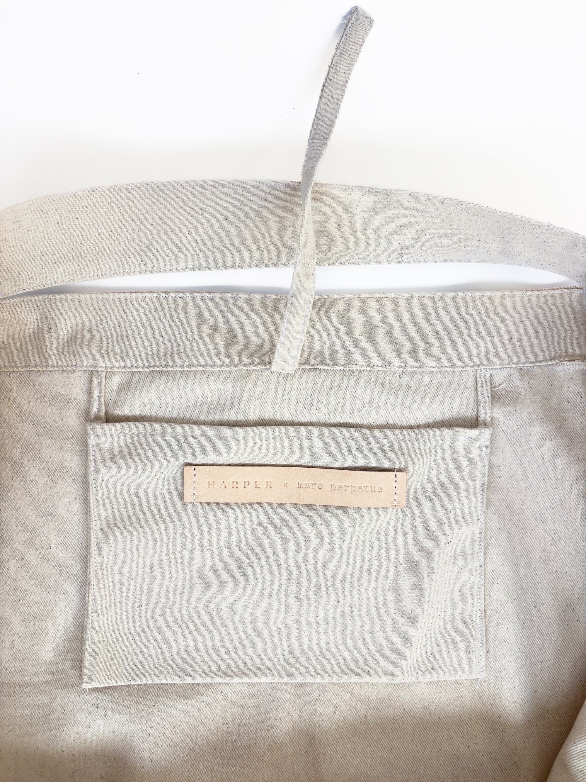 Beige beach tote bag with a visible Harper x Mare Perpetua label on a white background