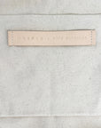 Close-up of a leather label with HARPER X MARE PERPETUA text on a textured gray fabric background