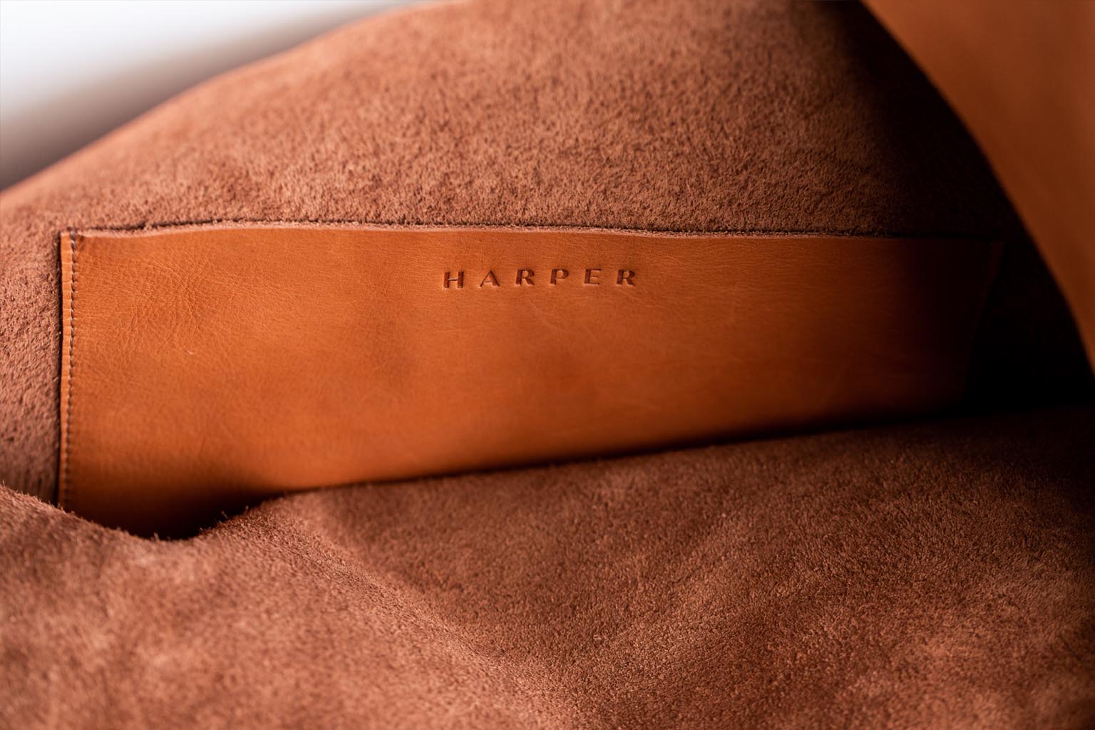 The interior of large, soft cognac brown leather shoulder bag, showing the inside pocket with stitching and the &quot;Harper&quot; logo.