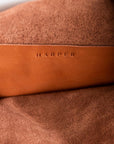 The interior of large, soft cognac brown leather shoulder bag, showing the inside pocket with stitching and the "Harper" logo.