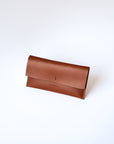 A light brown leather envelope wallet sits against a white background. It has the "Harper" logo heat stamped at the bottom, with the top flap secured by a brass button stud. 